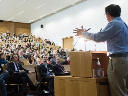 Lecture hall with speaker in foreground and attendees listening at second Open Science Meeting